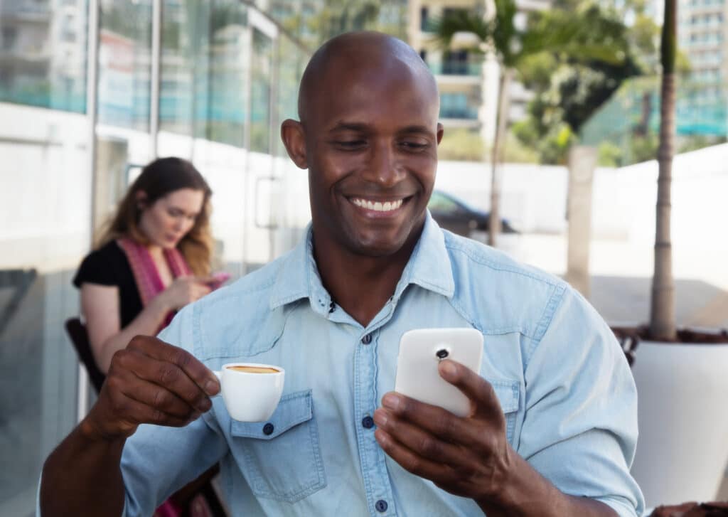 African man receiving message on phone in a coffee shop.